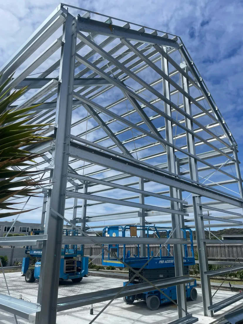 The complete galvanised portal frame skeleton of Shed Home #03 standing against a blue sky