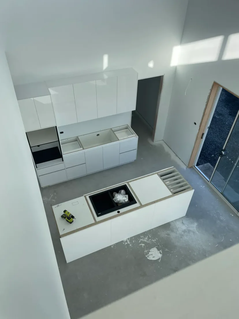 The kitchen joinery being installed against the bare slab